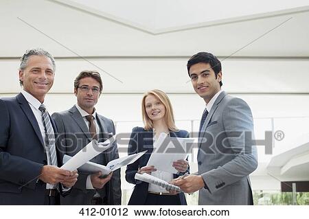 Portrait of smiling business people reviewing paperwork View Large Photo Image Stock Image - Portrait of smiling business people reviewing paperwork. Fotosearch
