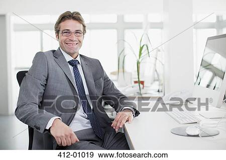 Portrait of smiling businessman at desk View Large Photo Image Stock Photo - Portrait of smiling businessman at desk. Fotosearch