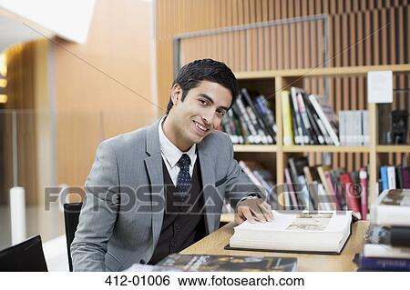Portrait of smiling businessman reading book in library View Large Photo Image Stock Photograph - Portrait of smiling businessman reading book in library. Fotosearch