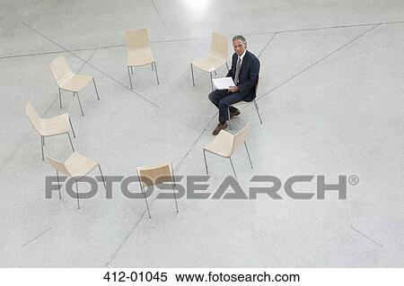 Portrait of smiling businessman sitting in circle of chairs View Large Photo Image Stock Photography - Portrait of smiling businessman sitting in circle of chairs. Fotosearch