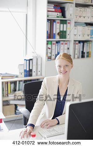 Portrait of smiling businesswoman at desk in office View Large Photo Image Stock Image - Portrait of smiling businesswoman at desk in office. Fotosearch
