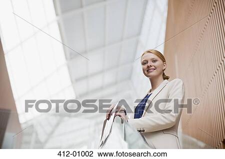 Portrait of smiling businesswoman holding report in modern office View Large Photo Image Stock Image - Portrait of smiling businesswoman holding report in modern office. Fotosearch