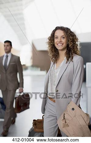 Picture - Portrait of smiling businesswoman with suitcase at airport. Fotosearch