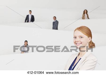 Portrait of smiling businesswoman with co-workers on staircase in background View Large Photo Image Picture - Portrait of smiling businesswoman with co-workers on staircase in background. Fotosearch
