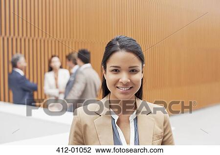 Portrait of smiling businesswoman with co-workers meeting in background View Large Photo Image Stock Image - Portrait of smiling businesswoman with co-workers meeting in background. Fotosearch