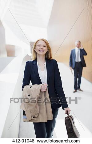 Stock Photograph - Portrait of smiling businesswoman with coat and briefcase. Fotosearch