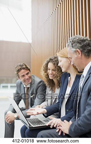 Smiling business people meeting with laptop View Large Photo Image Stock Photo - Smiling business people meeting with laptop. Fotosearch