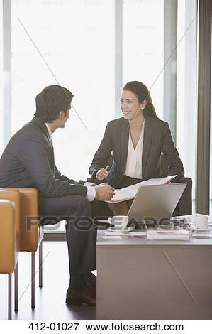 Stock Photo - Smiling businessman and businesswoman reviewing paperwork. Fotosearch