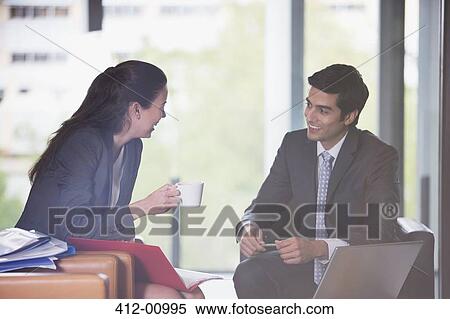 Smiling businessman and businesswoman with coffee, laptop and paperwork View Large Photo Image Stock Photography - Smiling businessman and businesswoman with coffee, laptop and paperwork. Fotosearch