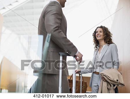 Smiling businesswoman talking to businessman in airport View Large Photo Image Stock Photo - Smiling businesswoman talking to businessman in airport. Fotosearch
