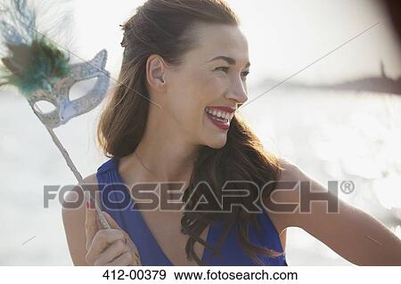 Stock Photo - Close up of smiling woman holding mask. Fotosearch