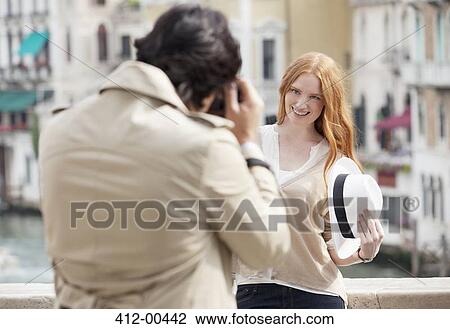 Man photographing smiling woman holding hat in Venice View Large Photo Image Stock Image - Man photographing smiling woman holding hat in Venice. Fotosearch