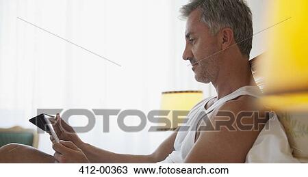Stock Image - Man using digital tablet in bed. Fotosearch
