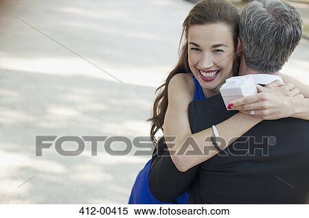 Stock Photography - Portrait of smiling woman receiving gift from man. Fotosearch