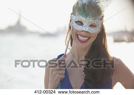 Portrait of smiling woman wearing mask at waterfront in Venice View Large Photo Image Picture - Portrait of smiling woman wearing mask at waterfront in Venice. Fotosearch