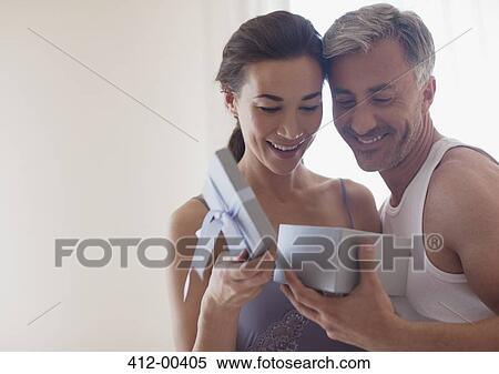 Stock Photography - Smiling couple opening gift box. Fotosearch