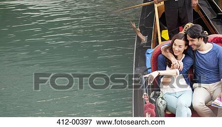 Smiling couple riding in gondola on canal in Venice View Large Photo Image Stock Photo - Smiling couple riding in gondola on canal in Venice. Fotosearch