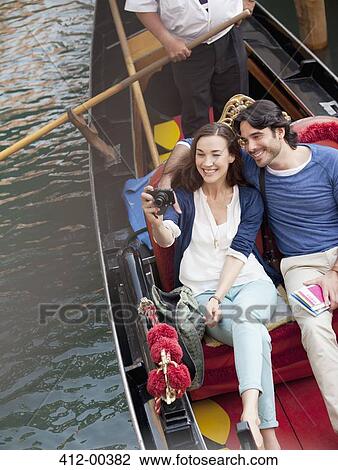 Smiling couple taking photographs in gondola on canal in Venice View Large Photo Image Stock Image - Smiling couple taking photographs in gondola on canal in Venice. Fotosearch
