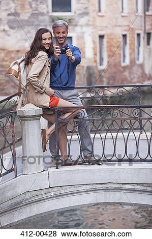 Stock Photo - Smiling couple taking self-portrait on footbridge in Venice. Fotosearch