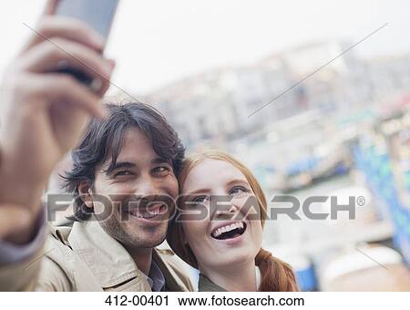 Smiling couple taking self-portrait with cell phone View Large Photo Image Stock Image - Smiling couple taking self-portrait with cell phone. Fotosearch
