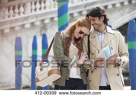 Stock Photo - Smiling couple walking with map in Venice. Fotosearch