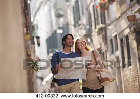 Stock Image - Smiling couple with map on narrow street in Venice. Fotosearch