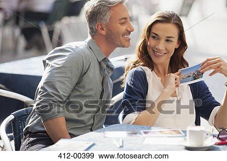 Smiling couple with postcard at sidewalk cafe View Large Photo Image Stock Photo - Smiling couple with postcard at sidewalk cafe. Fotosearch