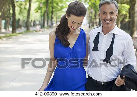Stock Image - Smiling well-dressed couple in park. Fotosearch
