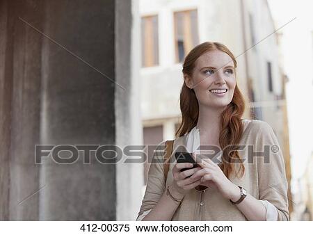 Stock Photography - Smiling woman holding cell phone. Fotosearch