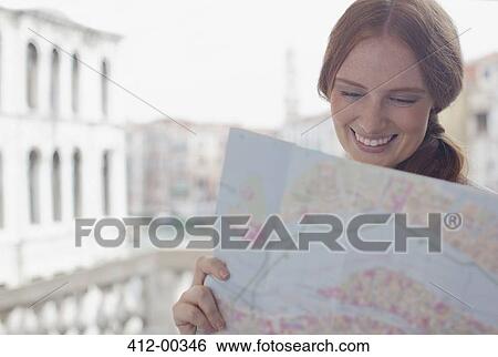 Smiling woman looking down at map View Large Photo Image Stock Photograph - Smiling woman looking down at map. Fotosearch