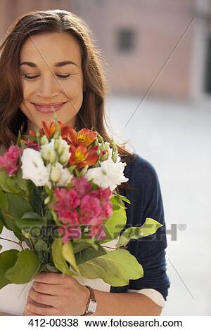 Smiling woman smelling bouquet of flowers View Large Photo Image Stock Photo - Smiling woman smelling bouquet of flowers. Fotosearch