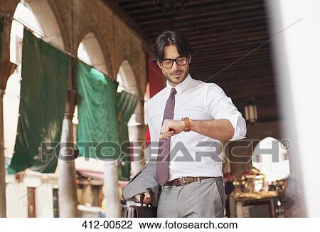 Businessman checking wristwatch in outdoor market View Large Photo Image Stock Image - Businessman checking wristwatch in outdoor market. Fotosearch