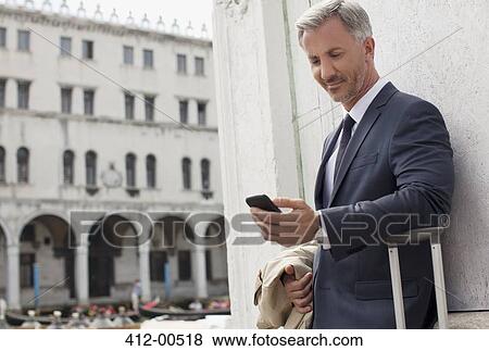 Stock Photo - Businessman looking down at cell phone in Venice. Fotosearch