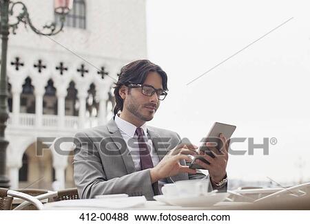 Businessman using digital tablet at sidewalk cafe in Venice View Large Photo Image Stock Photo - Businessman using digital tablet at sidewalk cafe in Venice. Fotosearch