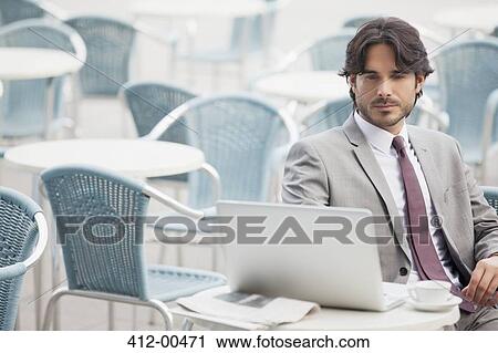Businessman using laptop at sidewalk cafe View Large Photo Image Stock Image - Businessman using laptop at sidewalk cafe. Fotosearch