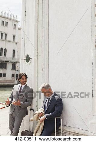 Businessmen with suitcases talking and leaning against building in Venice View Large Photo Image Stock Image - Businessmen with suitcases talking and leaning against building in Venice. Fotosearch