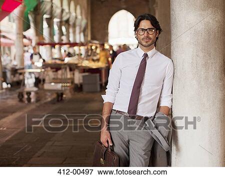 Portrait of confident businessman leaning against pillar at outdoor market View Large Photo Image Stock Photo - Portrait of confident businessman leaning against pillar at outdoor market. Fotosearch