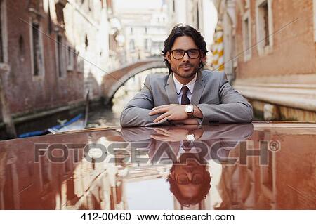 Portrait of serious businessman riding boat in canal in Venice View Large Photo Image Stock Image - Portrait of serious businessman riding boat in canal in Venice. Fotosearch