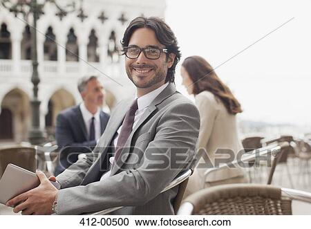 Portrait of smiling businessman holding digital tablet at sidewalk cafe in Venice View Large Photo Image Stock Image - Portrait of smiling businessman holding digital tablet at sidewalk cafe in Venice. Fotosearch