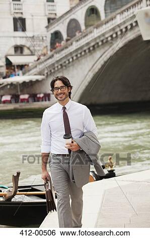 Portrait of smiling businessman with coffee walking along canal in Venice View Large Photo Image Stock Photograph - Portrait of smiling businessman with coffee walking along canal in Venice. Fotosearch