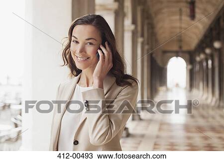 Portrait of smiling businesswoman talking on cell phone in corridor View Large Photo Image Stock Image - Portrait of smiling businesswoman talking on cell phone in corridor. Fotosearch