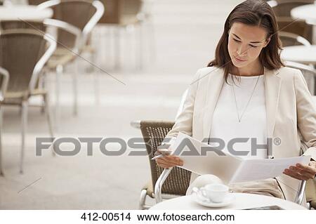 Picture - Serious businesswoman reading paperwork at sidewalk cafe. Fotosearch
