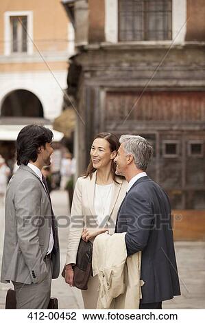 Stock Image - Smiling business people talking in street. Fotosearch