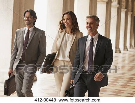Stock Photo - Smiling business people walking along corridor. Fotosearch