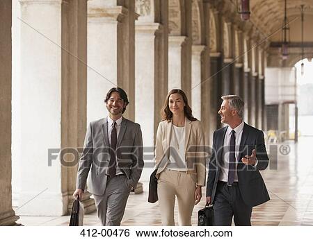 Stock Photograph - Smiling business people walking along corridor. Fotosearch
