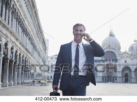 Smiling businessman talking on cell phone and walking through St. Mark's Square in Venice View Large Photo Image Stock Image - Smiling businessman talking on cell phone and walking through St. Mark's Square in Venice. Fotosearch