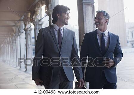 Smiling businessman walking along corridor View Large Photo Image Stock Image - Smiling businessman walking along corridor. Fotosearch