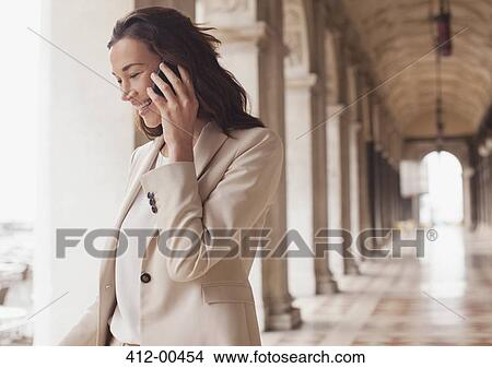 Smiling businesswoman talking on cell phone in corridor View Large Photo Image Picture - Smiling businesswoman talking on cell phone in corridor. Fotosearch