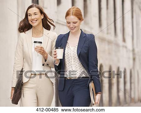 Smiling businesswomen walking with coffee View Large Photo Image Stock Photography - Smiling businesswomen walking with coffee. Fotosearch