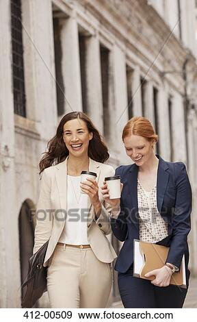 Stock Photo - Smiling women walking with coffee. Fotosearch